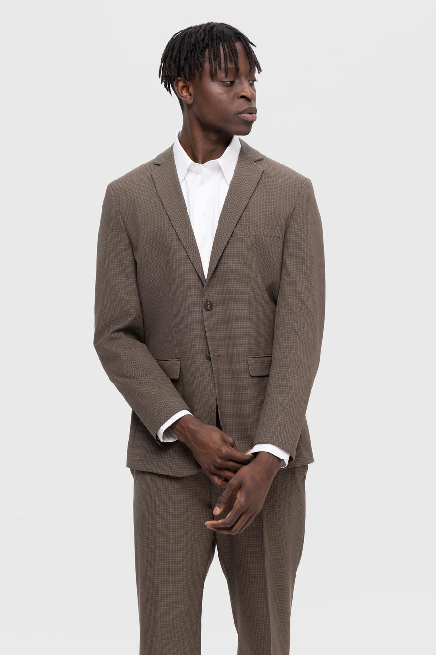 Man in bruin kostuum en wit overhemd.