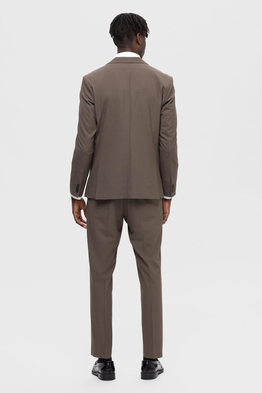 Achterkant van een man in een bruin pak.