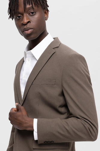 Man in bruin geruit jas met wit overhemd.
