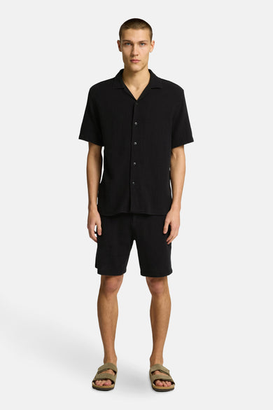 Short noir de SELECTED, associé à un t-shirt noir et des sandales.