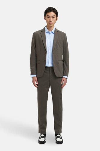 Blazer marron de SELECTED porté sur un chemisau bleu clair, avec des pantalons coordonnés et des chaussures noir et blanc.