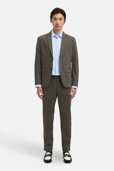Blazer marron de SELECTED porté sur un chemisau bleu clair, avec des pantalons coordonnés et des chaussures noir et blanc.