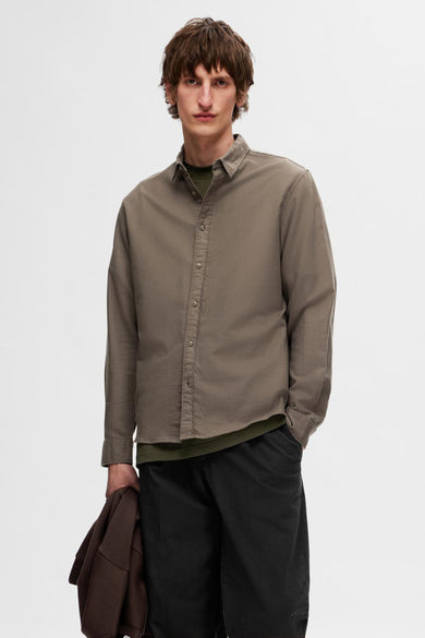 Mauve, chemise à manches longues de SELECTED, avec un t-shirt vert en dessous, associée à des pantalons noirs et des baskets.