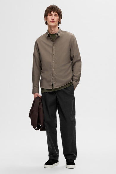 Bruin, lange mouwen overhemd van SELECTED, met een groen shirt eronder, gecombineerd met zwarte broeken en sneakers.