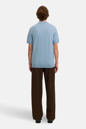Polo bleu à manches courtes de SELECTED, avec un design uni, porté avec un pantalon marron et des chaussures noires, vu de dos.