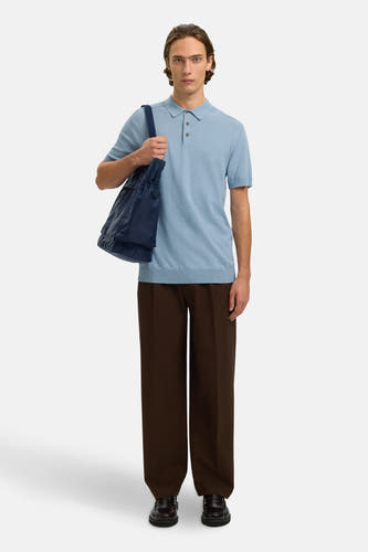 Polo bleu à manches courtes de SELECTED, porté avec un pantalon marron et des mocassins en cuir, avec un sac bleu porté sur l'épaule.