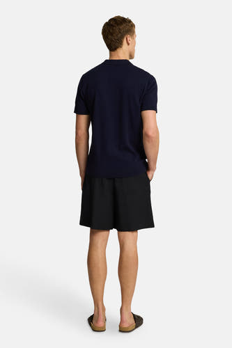 T-shirt bleu à manches courtes de SELECTED, vu de derrière, associé à des short noirs et des sandales.