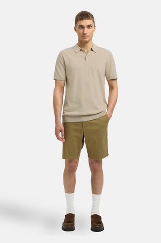 Beige polo met korte mouwen van SELECTED, gedragen met kaki shorts, witte sokken en bruine loafers.
