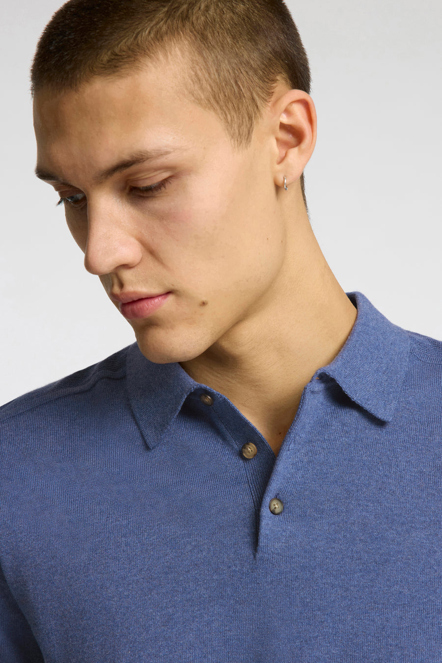 Polo en maille bleu à manches courtes de SELECTED avec boutons marron, porté par un homme.
