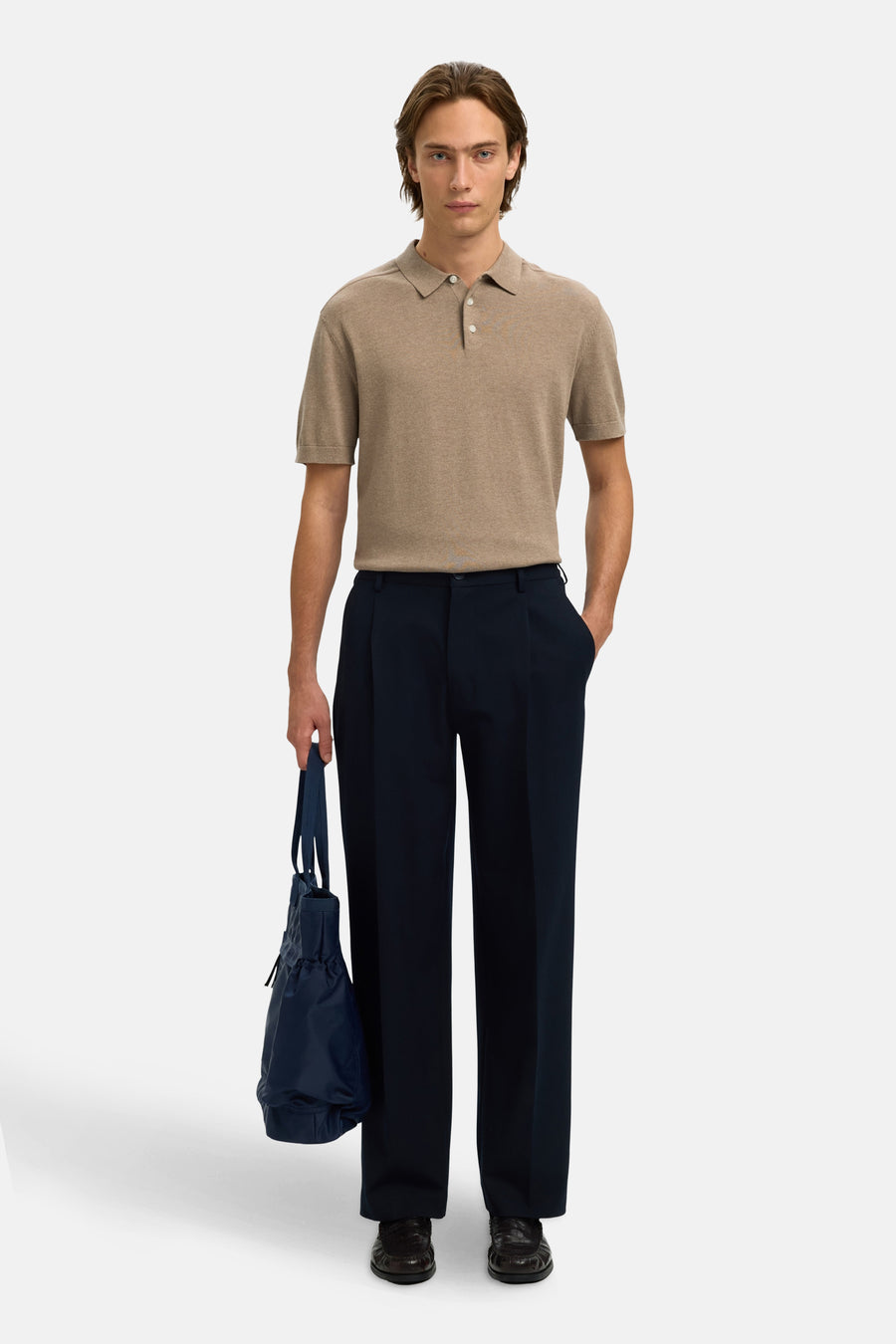 Polo à manches courtes marron de SELECTED, avec fermeture à boutons et portée avec un pantalon bleu foncé et un sac.