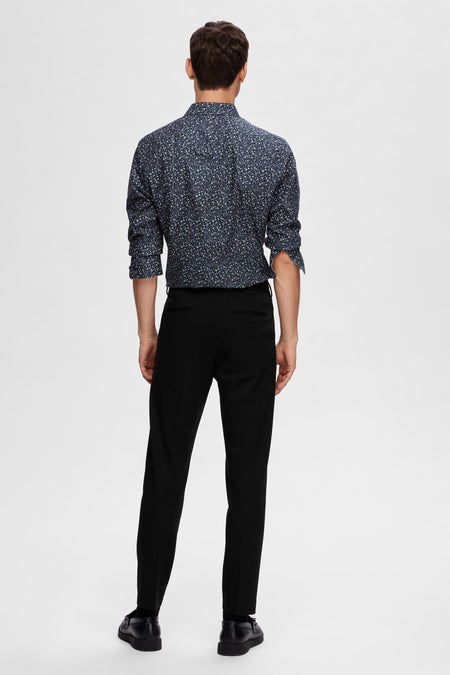Pantalon de costume noir SELECTED, vu de l'rièrerière combiné avec un chemisier bleu à fleurs et des chaussures noires.