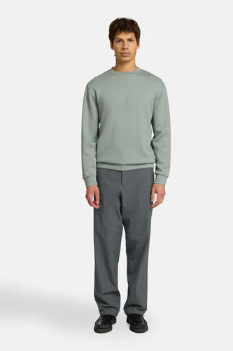 Groene sweater met ronde hals van SELECTED, van gladde stof, gedragen door een man met donkergrijze broek en zwarte loafers.