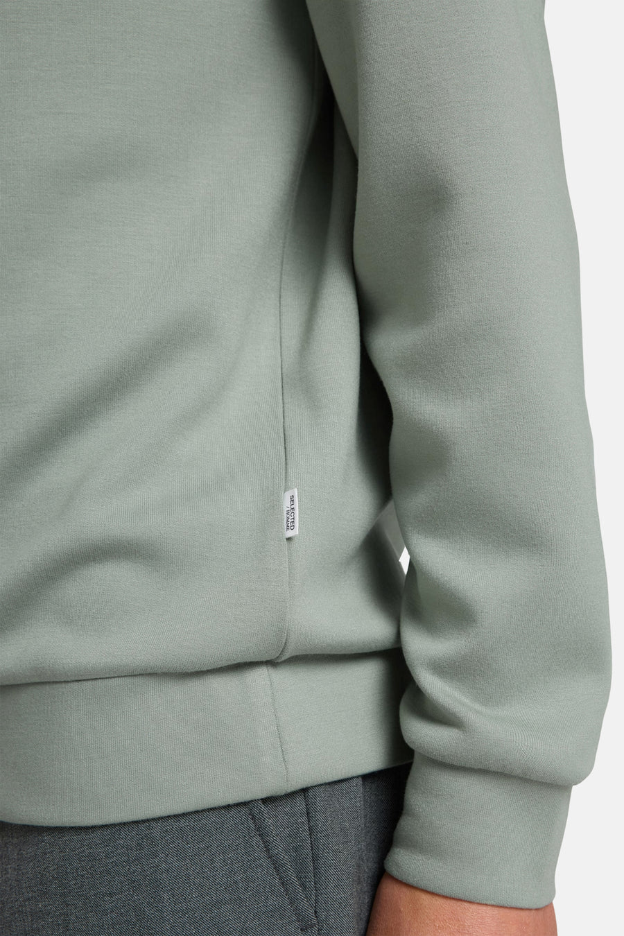 Pull vert de SELECTED avec des bords côtelés et une étiquette blanche sur la couture latérale.