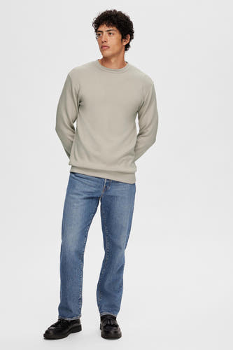 Ecru sweater van SELECTED, gecombineerd met jeans en zwarte schoenen tegen een witte achtergrond.
