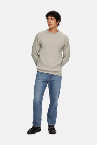 Ecru sweater van SELECTED, gedragen met blauwe jeans en zwarte leren schoenen.
