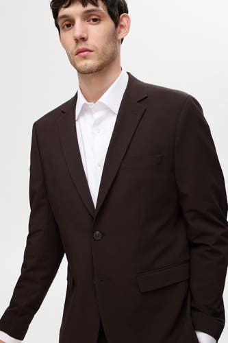 Blouse blanche à manches longues de SELECTED, portée sous un colbert marron.