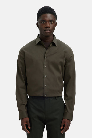 Chemise verte à manches longues de SELECTED, en tissu uni avec des rayures verticales, portée avec un pantalon foncé.