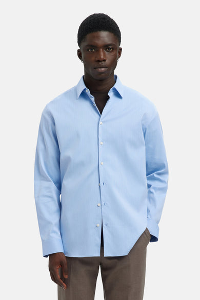 Chemise bleue à manches longues de SELECTED, avec col boutonné et portée avec un pantalon marron.