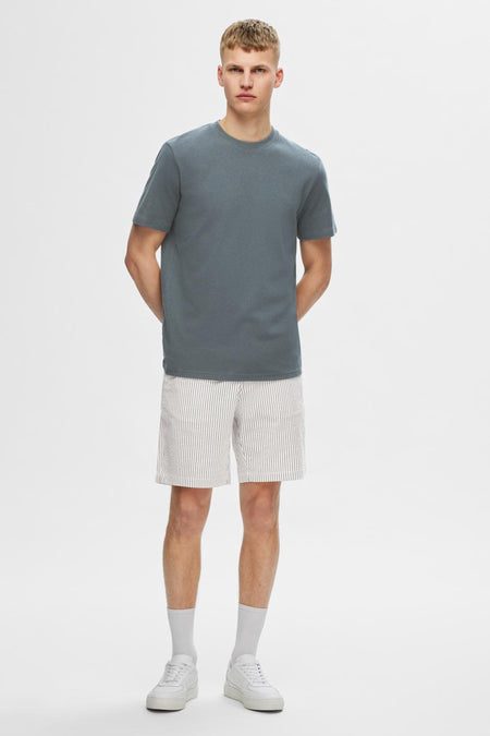 T-shirt gris à manches courtes de SELECTED, porté avec des shorts rayés, des chaussettes blanches et des baskets blanches.