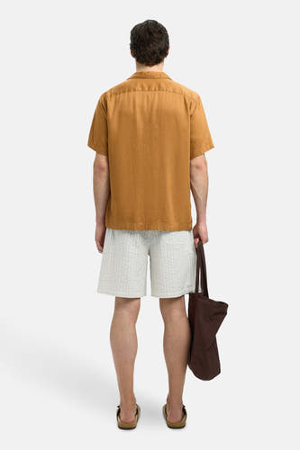Chemise beige à manches courtes de SELECTED, dos, associée à des shorts rayés et une sacoche brune.