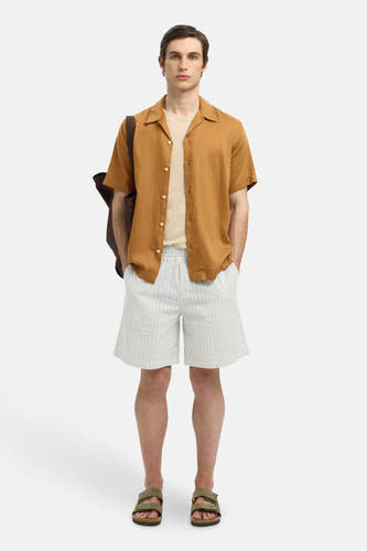Chemise beige à manches courtes de SELECTED, avec un col ouvert et portée sur un T-shirt.