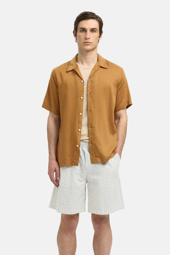 Chemise beige à manches courtes de SELECTED, portée sur un T-shirt, avec un short rayé.
