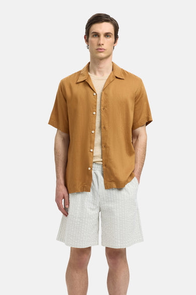 Chemise beige à manches courtes de SELECTED, portée sur un T-shirt, avec un short rayé.