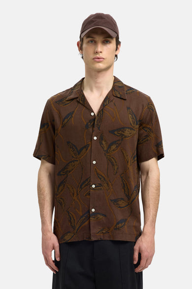 Chemise brune à manches courtes de SELECTED, avec un motif de feuilles et une casquette de baseball brune.