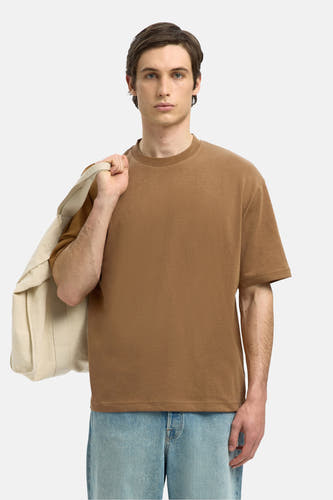 T-shirt marron à manches courtes de SELECTED, porté avec des jeans bleu clair et des sandales, avec une sacque blanche sur l'épaule.