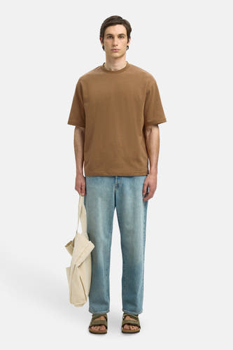 T-shirt marron à manches courtes de SELECTED, porté avec des jeans bleus, des sandales et un sac en toile beige.