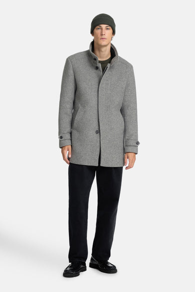 Grijs korte jas van SELECTED, met knoopsluiting, op een model met een donkere broek en loafers.
