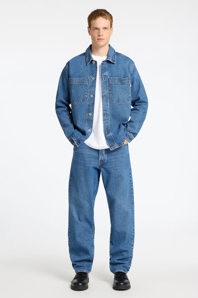 T-shirt en jeans en denim bleu de SELECTED, porté sur un T-shirt blanc, avec des jeans coordonnés et des chaussures noires.
