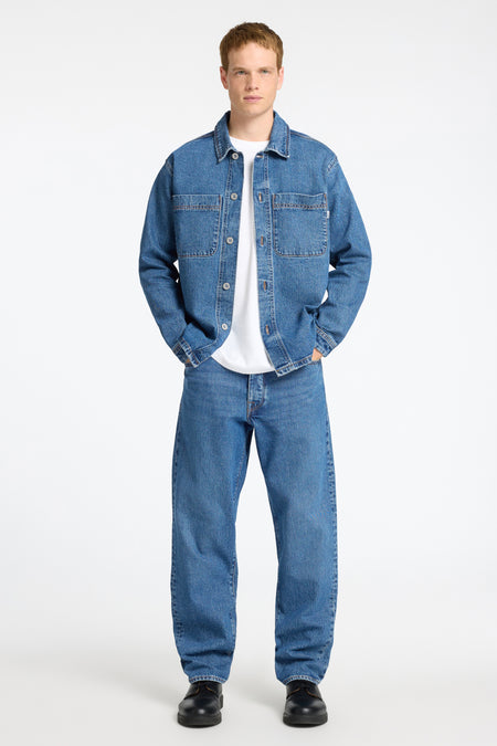T-shirt en jeans en denim bleu de SELECTED, porté sur un T-shirt blanc, avec des jeans coordonnés et des chaussures noires.