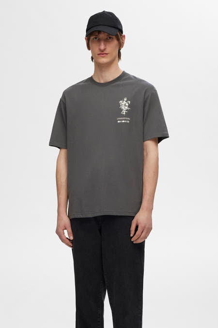 T-shirt gris à manches courtes de SELECTED, avec imprimé floral sur la poitrine, associé à un jean noir.