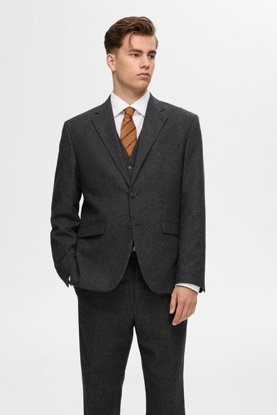 Blazer vert de SELECTED, avec une subtile texture, porté sur un chemisier blanc et une cravate rayée marron.