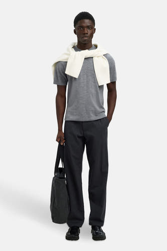 Sweat-shirt gris de SELECTED, porté avec un sweat-shirt blanc sur les épaules, associé à une pantalon foncé et un sac.