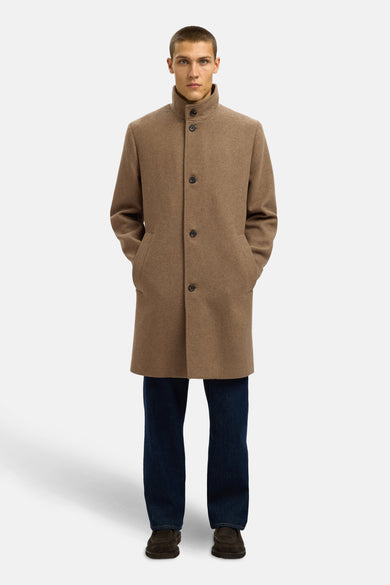 Manteau long marron de SELECTED, avec fermeture à boutons et poches, porté sur des jeans foncés et des chaussures marron foncé.
