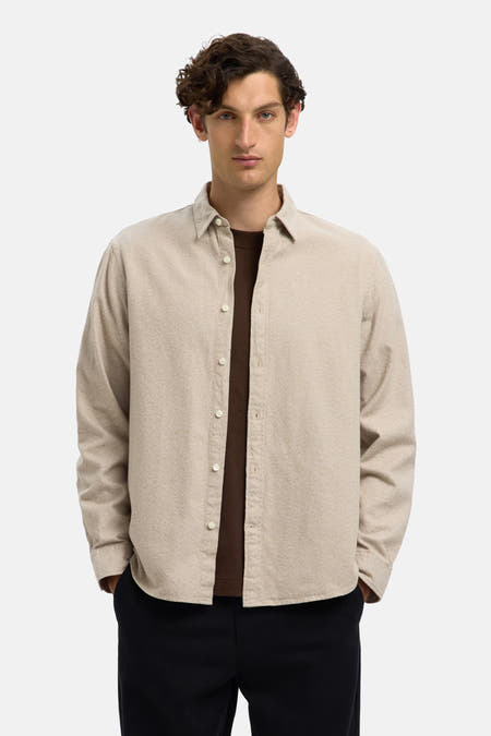 Chemise beige à longues manches de SELECTED, portée sur une chemise brune et un pantalon noir.