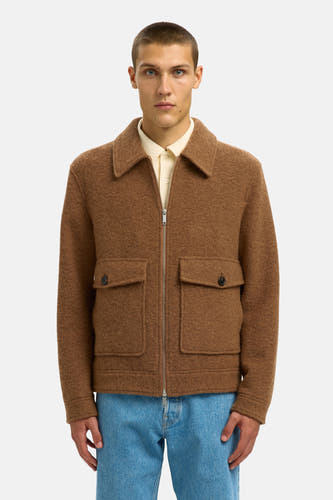 Manteau brun court de SELECTED, avec fermeture éclair et poches brodées, porté sur une polo claire et des jeans bleus.