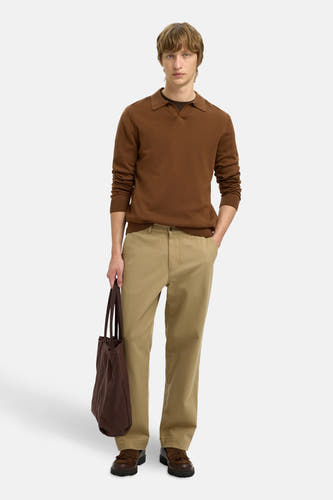 Pull à col V en cuir de SELECTED, avec des manches longues, associé à un pantalon kaki et une sacoche brune.