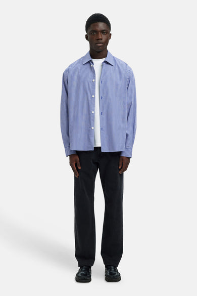 Chemise bleue à manches longues de SELECTED, avec des rayures verticales, portée sur un T-shirt blanc et un pantalon noir et des chaussures.