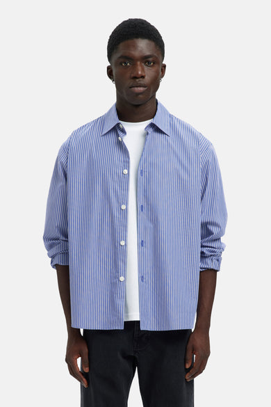 Chemise bleue rayée à manches longues de SELECTED, avec des rayures blanches, portée sur un T-shirt blanc et un pantalon noir.