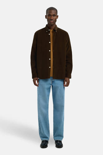 Chemise brune à longues manches de SELECTED, portée sur une chemise brune et des jeans bleus avec des chaussures noires.