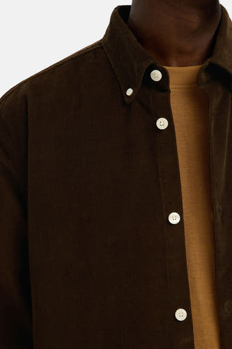 Chemise en corduroy marron à longues manches de SELECTED, avec des boutons blancs et une chemise marron en dessous.