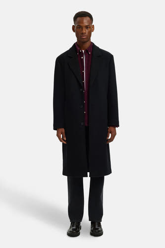 Chemise de couleur bordeaux à longues manches de SELECTED, avec une subtile texture, portée sous un manteau noir et des jeans foncés.