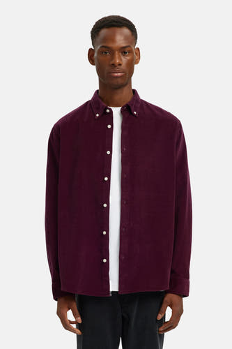 Chemise de couleur bordeaux à longues manches de SELECTED, portée sur un T-shirt blanc et un pantalon foncé.