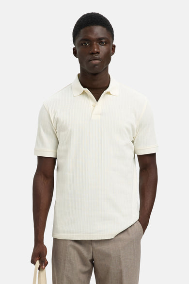 Polo écru à manches courtes de SELECTED, avec des rayures verticales subtiles et porté avec un pantalon marron.