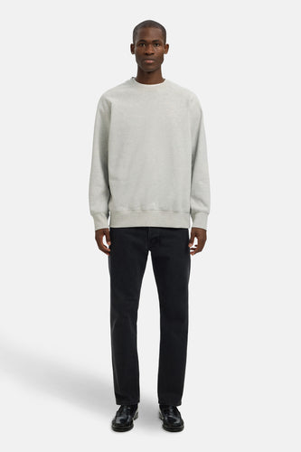 Man die grijze trui en zwarte jeans draagt, in de studio.