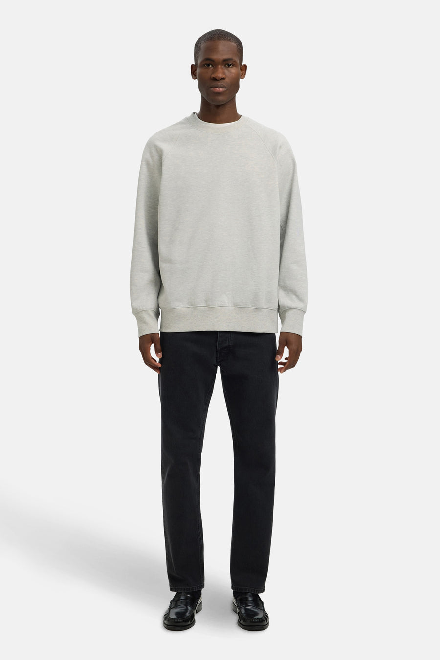 Man die grijze trui en zwarte jeans draagt, in de studio.