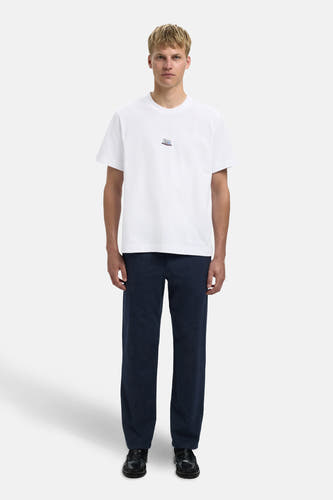 T-shirt blanc à manches courtes de SELECTED, avec une petite impression et associé à un pantalon foncé et des chaussures noires.